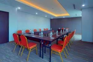 a conference room with a long table and red chairs at Java Lotus Hotel Jember in Jember +185 photos