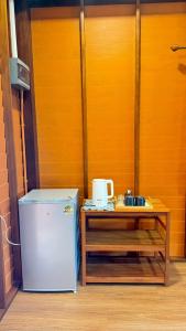 a small refrigerator and a table next to a door at Cheriya bungalow Kohyaonoi in Ban Laem Sai