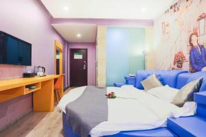 a hotel room with a bed and a desk and a tv at Shell Ganzhou Central Theme Hotel in Ganzhou