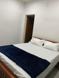 a bed with a blue and white blanket on it at The Lovely Home Stay in Munnar