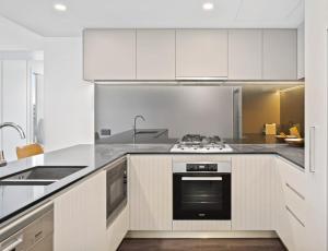 een keuken met witte kasten en een kookplaat oven bij Festival Towers Brisbane in Brisbane