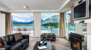 a living room with a couch and a large window at Oaks Queenstown Club Suites in Queenstown
