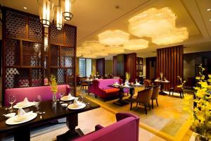 a restaurant with pink furniture and tables and chairs at New Century Hangzhou Grand Hotel in Xiaoshan