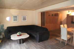 a living room with a black couch and a table at Appartementhaus Vierjahreszeiten in Willingen