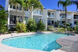 a swimming pool in front of a building at St Tropez 8 - Waterfront Retreat with Rooftop Spa & Sauna in Noosa Heads