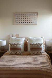 une chambre avec un lit avec des oreillers dessus dans l'établissement Fitzroy Olive Cottage, à Dubbo