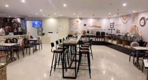 a restaurant with a bar with stools in a room at Shell Shanghai Songjiang District Xinqiao Town Xinqiao Hotel in Chunshen