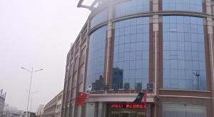un grand bâtiment en verre avec un panneau. dans l'établissement GreenTree Inn Heze Railway Station Hotel, à Zhaolou