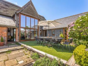 a patio with a table and chairs and an umbrella at Liston Hall Barn in Gosfield
