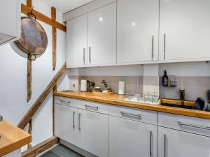 a kitchen with white cabinets and a sink at Liston Hall Barn in Gosfield +16 photos