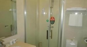 a bathroom with a shower with a glass door at GreenTree Inn Yixing Zhangzhu Express Hotel in Xinchating +85 photos