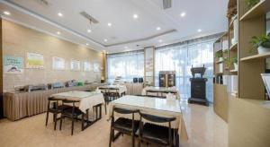 a restaurant with tables and chairs and a stove at GreenTree Inn Jiaxing Tongxiang Tudian Express Hotel in T'u-tien-shih