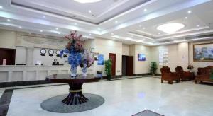 un vestíbulo con un jarrón de flores sobre una mesa en GreenTree Inn Shanghai Jiading Newtown MaLu Subway Station Business Hotel, en Jiading