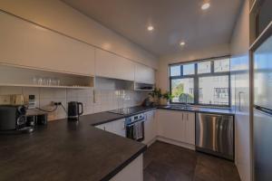 a kitchen with white cabinets and a large window at Elegant 3-Storey Townhouse with Garage Parking by Latimer Sq in Christchurch