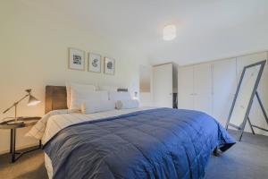 a bedroom with a large bed with a blue blanket at Elegant 3-Storey Townhouse with Garage Parking by Latimer Sq in Christchurch