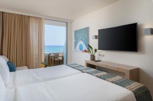 レティムノ・タウンにあるKriti Beach Hotelのベッドと薄型テレビがあるホテルの部屋