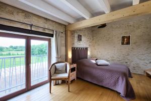 a bedroom with a bed and a large window at La Grange d'Oustaud in Vérac