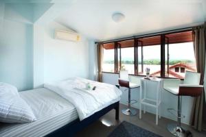 a bedroom with a bed and a desk and windows at The Royal Chiangkhan Boutique Hotel in Chiang Khan