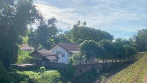 a white house with a fence next to a field at Mekong Sedone Hostel Neva Paris in Pakse