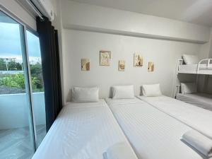 two beds in a room with a window at Comfy Hotels Suvarnabhumi Airport in Samut Prakan