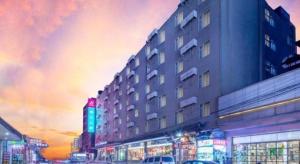 a tall building with neon signs in a city at Jinjiang Inn Kunming Changshui Airport in Kunming