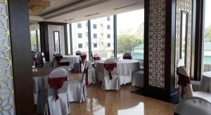 a restaurant with white tables and chairs and windows at Summer Hotel in Dong Quan