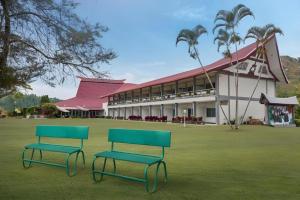two green benches sitting in front of a building at Patra Comfort Parapat in Parapat