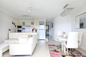 a white living room with white furniture and a kitchen at St Tropez 8 - Waterfront Retreat with Rooftop Spa & Sauna in Noosa Heads