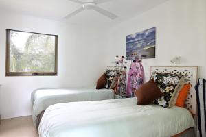a room with three beds and a ceiling fan at St Tropez 8 - Waterfront Retreat with Rooftop Spa & Sauna in Noosa Heads +29 photos