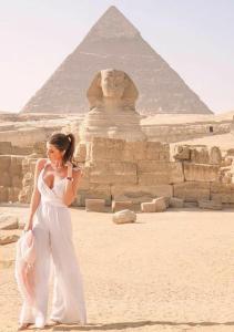kobieta w białej sukience stojąca przed piramidami w obiekcie sun 3 pyramids view inn w Kairze +10 zdjęć