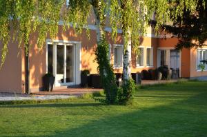 ein Haus mit einem Baum im Gras in der Unterkunft HOTEL MARIA in Gramatneusiedl