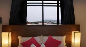 a bed with two red pillows and a large window at Iroom Hotel in Surat Thani +66 photos
