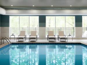a pool in a hotel with chairs and windows at Holiday Inn Express & Suite Milroy - Reedsville By IHG in Reedsville