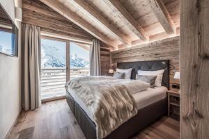 Un dormitorio con una cama grande y una ventana grande. en Aadla Walser-Chalets mit privater Sauna, Hotpot und Hotelservice, en Schröcken