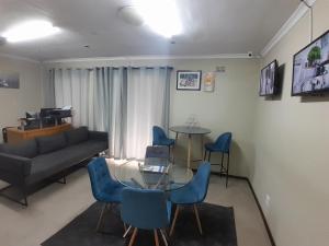 a living room with a glass table and blue chairs at GLOBALNEST guest house in Cape Town