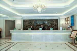 two people standing at a counter in a lobby at Vienna Classic Hotel Qingdao Huangdao in Huangdao