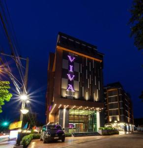 a building with a purple sign on it at night at Viva Residence in Ban Baen Phichit