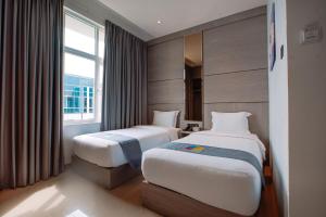 a hotel room with two beds and a window at The Quadrant Hotel KNO in Medan
