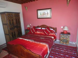 una camera da letto con un letto con una parete rossa di Dar Yanis a Rabat Altre 37 foto