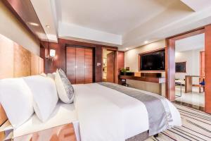 une chambre avec un grand lit blanc et une télévision dans l'établissement Moon Crescent Hotel (Chengdu West Steition Culture Palace Metro Stetion Branch), à Supoqiao