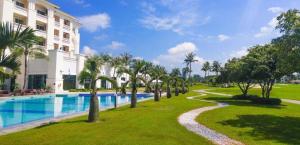 a resort with a pool and palm trees and a building at Sono Belle Haiphong in Trại Kênh