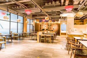 a restaurant with tables and chairs in a room with windows at James Joyce Coffetel Qinhuangdao Taiyangcheng Wenhua Road in Qinhuangdao
