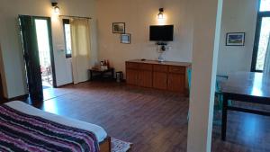 een woonkamer met een televisie en een houten vloer bij Anant Rasa Resort - Ranikhet in Shitlakhet
