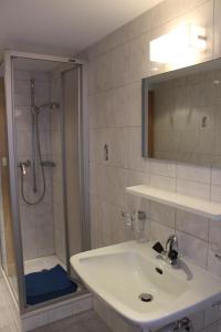 a white bathroom with a sink and a shower at Mittaghornblick in Saas-Grund