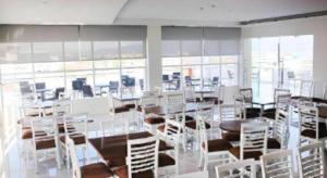 a room with white chairs and tables and windows at Everbright Ambon Hotel in Batu Merah +26 photos