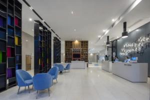 a library with blue chairs and tables in a building at Echarm Hotel Beihai Railway Station in Dianbailiao