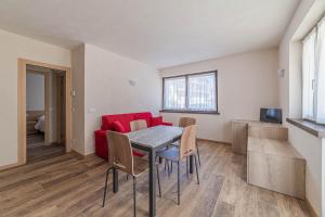 a living room with a table and a red couch at Casa Scola in Falcade