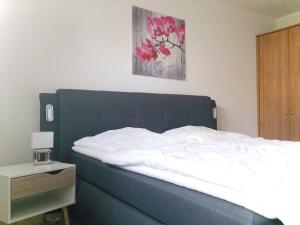 a bedroom with a bed with a blue headboard and a table at GUWO Gästewohnung Friedrich-Schiller-Str 28 in Sprucke