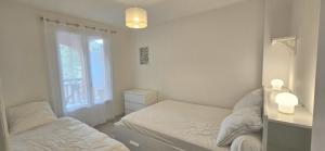 a bedroom with two twin beds and a window at Appartement proche centre-ville et plages in Cavalaire-sur-Mer
