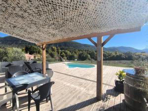 a pergola with a table and chairs on a deck at Entre Bois et Lumiere in Le Brusquet